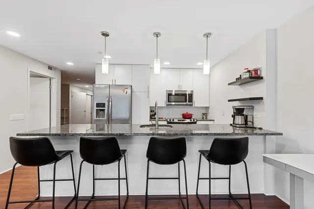 a kitchen with stainless steel appliances a dining table chairs and white cabinets
