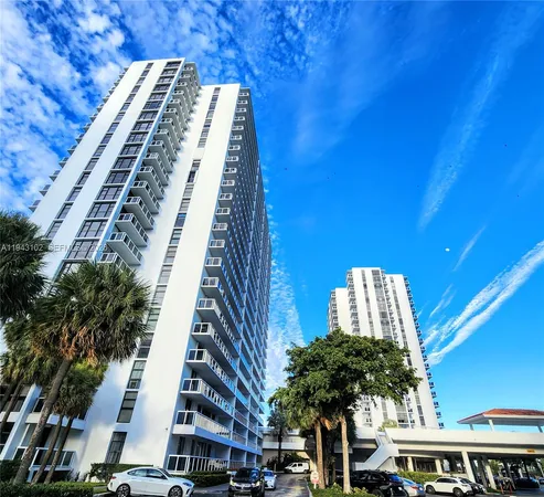 a front view of a multi story residential apartment building with yard and parking space