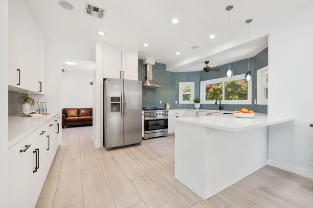 a kitchen with stainless steel appliances kitchen island granite countertop a refrigerator and a stove top oven
