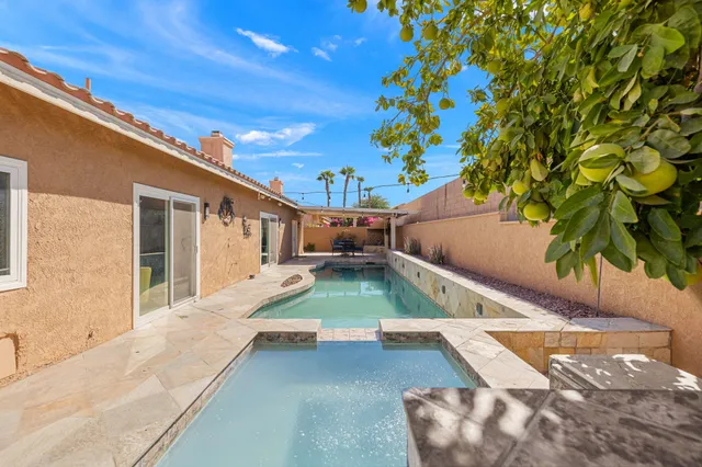 a view of a house with pool fire pit a table and chairs
