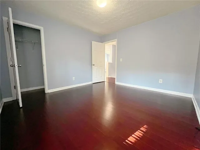 an empty room with wooden floor and windows with curtains
