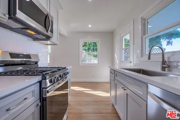 a kitchen with stainless steel appliances granite countertop a stove a sink and a microwave