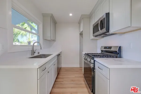 a kitchen with stainless steel appliances granite countertop a sink and a stove top oven