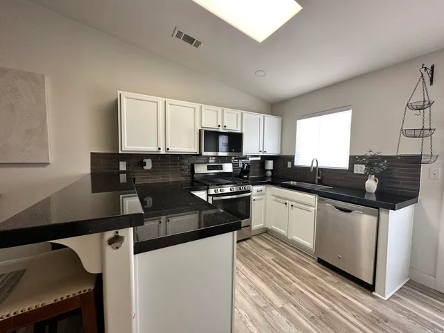 a kitchen with stainless steel appliances granite countertop a stove a sink and a microwave