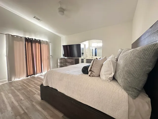 a large bed sitting in a bedroom next to a window and a flat screen tv