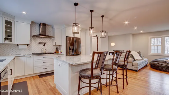 a kitchen with stainless steel appliances kitchen island granite countertop a table chairs in it and wooden floors