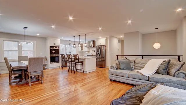 a living room with furniture and a dining table with wooden floor