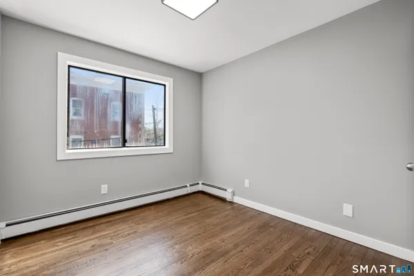 a view of an empty room with wooden floor and a window