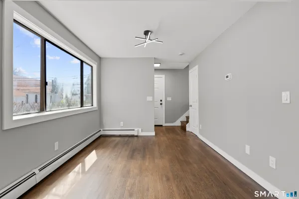 a view of an empty room with a window and wooden floor