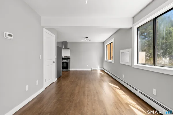 a view of an empty room with a window and wooden floor