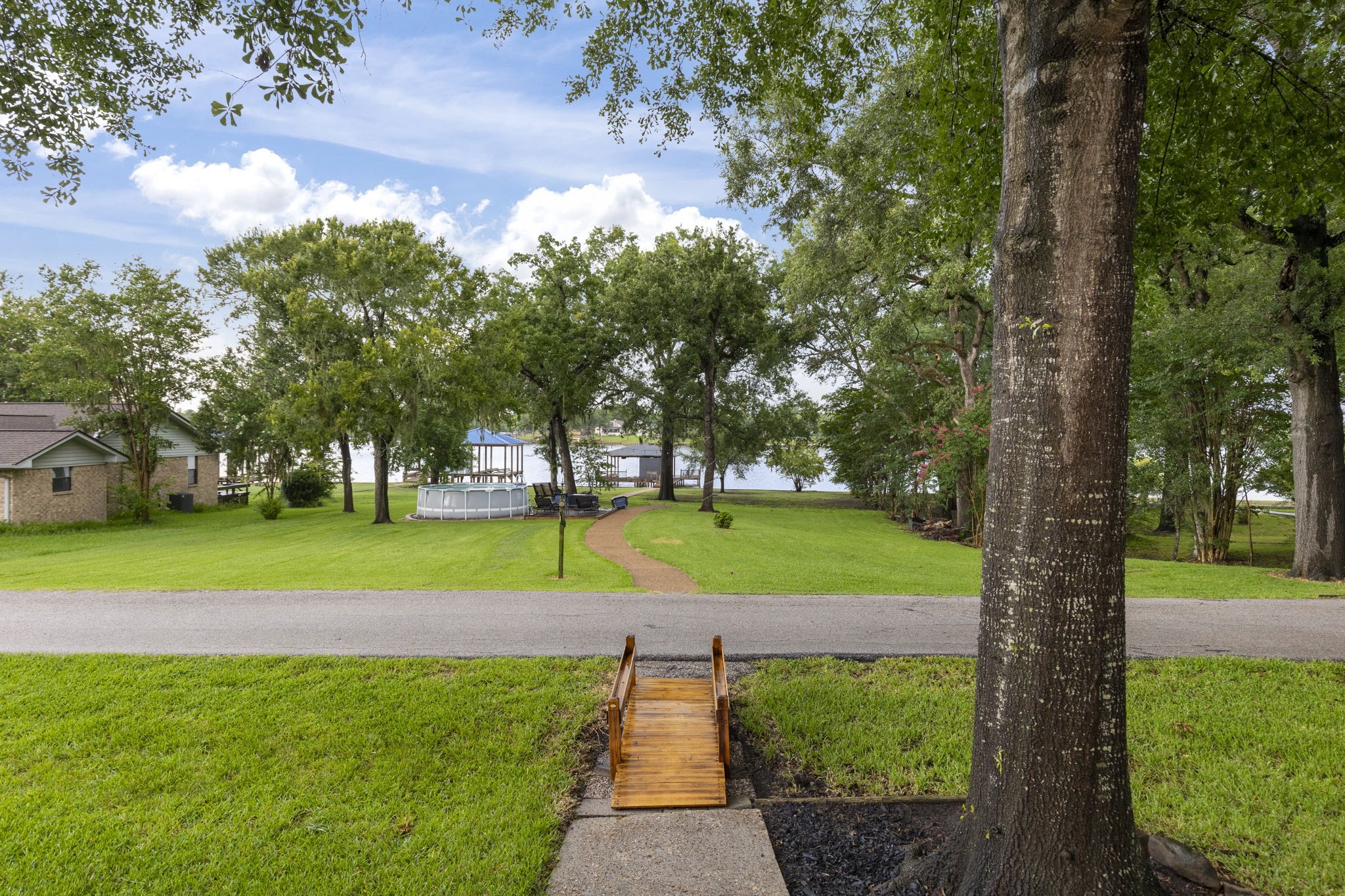 245 Lakeland Road Huntsville, TX 77320 - Photo 41 of 49 The backyard offers serene lakefront with a lightly traveled neighborhood road nestled between the house and the water's edge, providing a peaceful and picturesque setting.