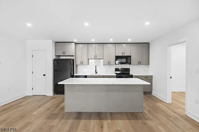 a large kitchen with stainless steel appliances a large counter top a stove and a refrigerator