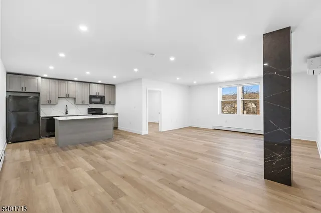 a view of kitchen with kitchen island a sink wooden floor and a refrigerator