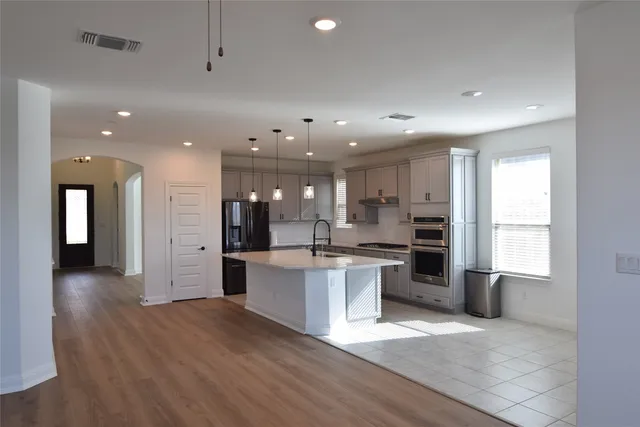 a large kitchen with stainless steel appliances kitchen island a large counter top and a sink