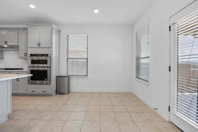 a kitchen with a refrigerator a stove top oven and white cabinets