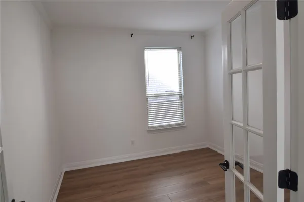 a view of an empty room with wooden floor and a window