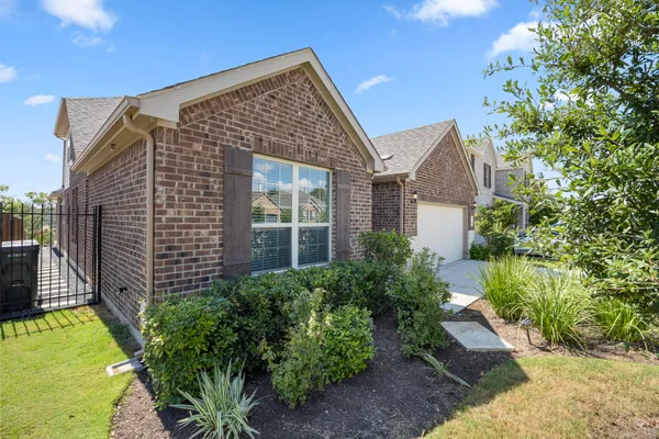 a view of a brick house with a yard and plants