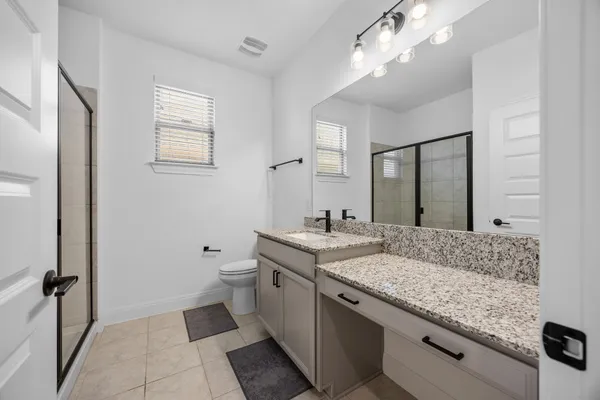 a bathroom with a granite countertop sink a toilet and mirror