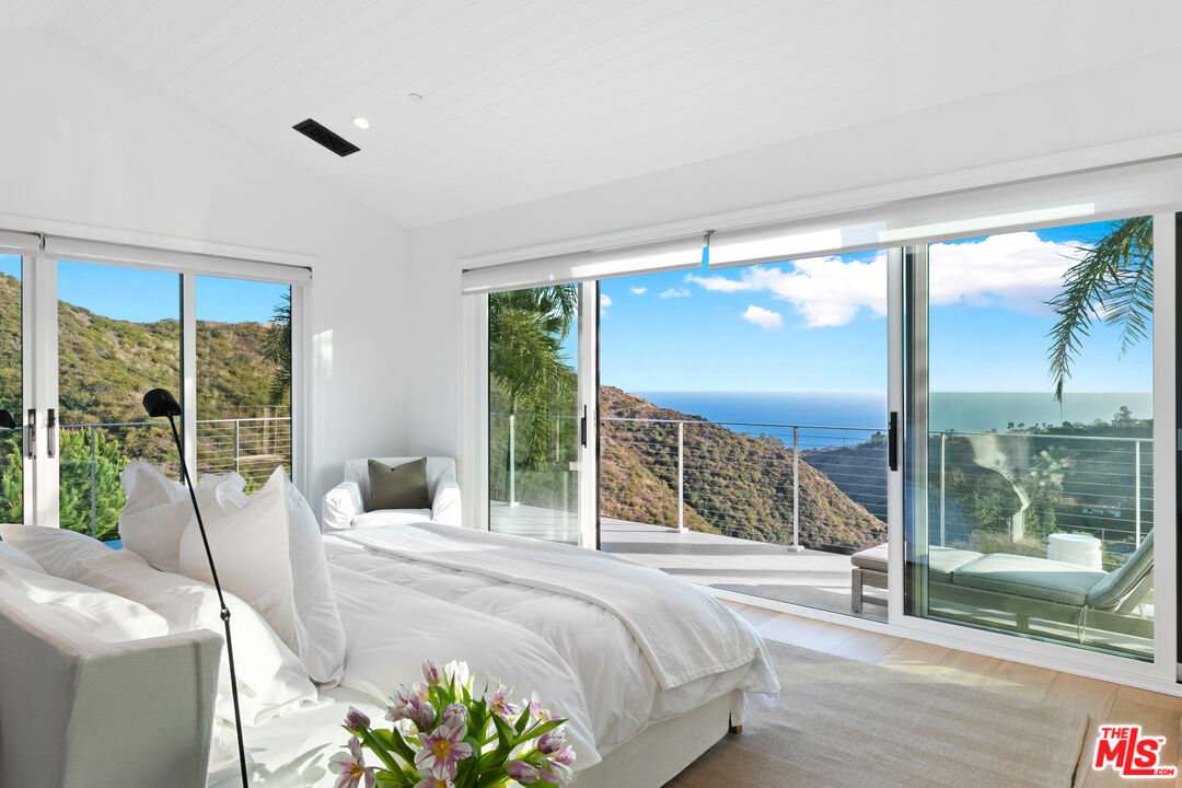26575 Ocean View Drive Malibu, CA 90265 - Photo 12 of 40 a bedroom with a bed and large glass window