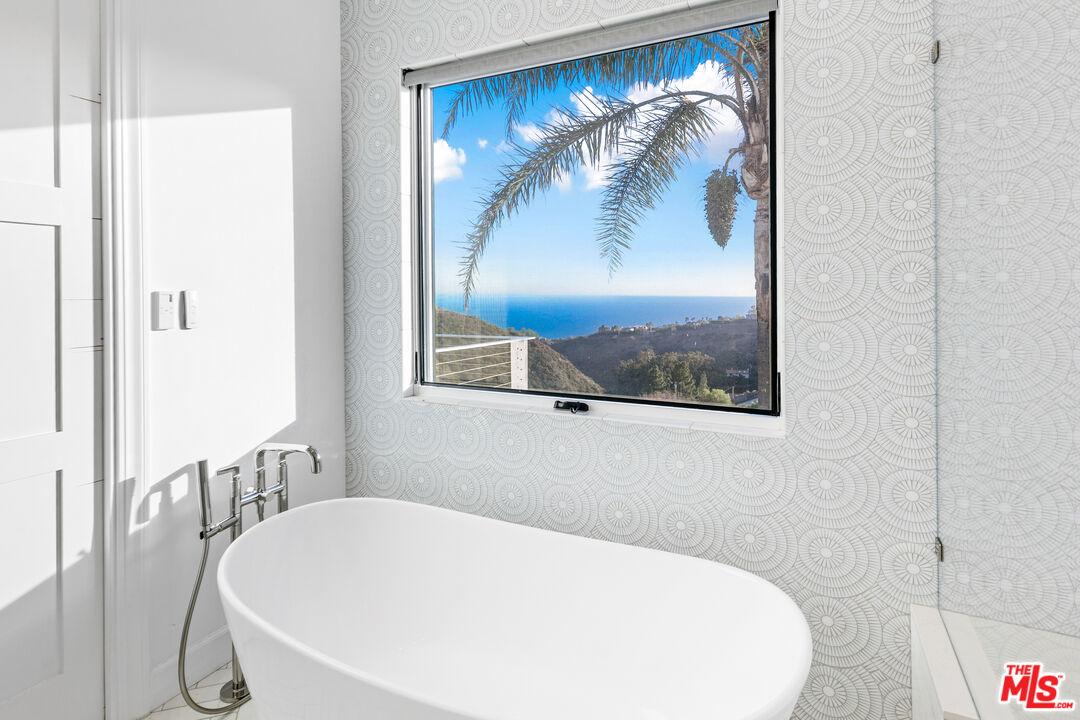 26575 Ocean View Drive Malibu, CA 90265 - Photo 18 of 40 a bathroom with a bathtub and a painting on the wall