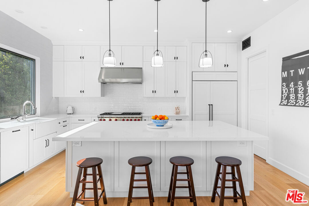 26575 Ocean View Drive Malibu, CA 90265 - Photo 7 of 40 a kitchen with granite countertop a table chairs stove and white cabinets