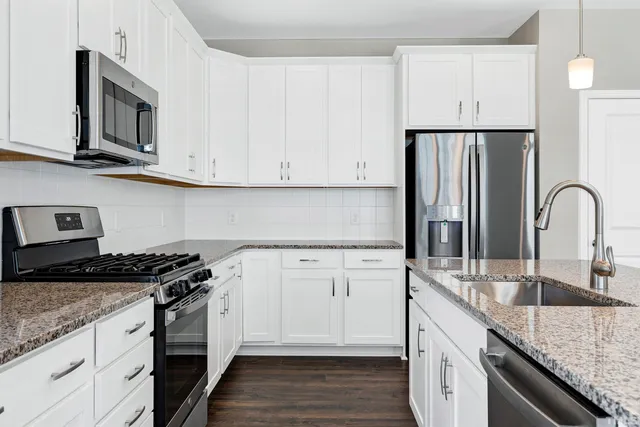 a kitchen with granite countertop a sink stove and cabinets