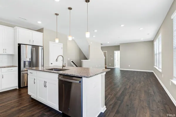 a kitchen with stainless steel appliances granite countertop a sink a stove a refrigerator and island with wooden floor