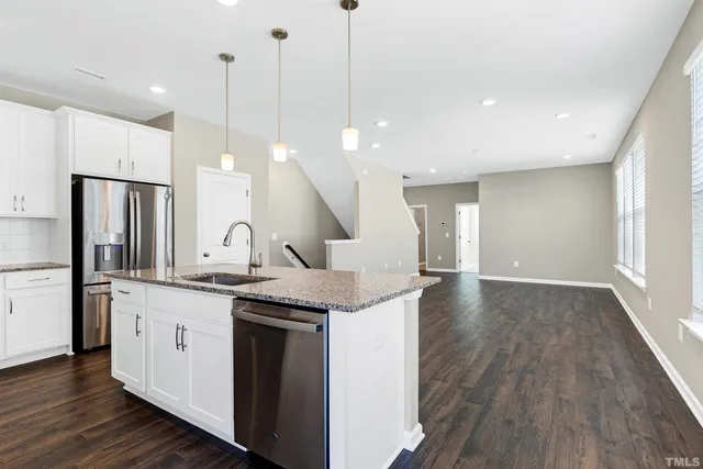 a kitchen with stainless steel appliances granite countertop a sink a stove a refrigerator and island with wooden floor