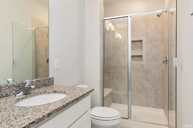 a bathroom with a granite countertop sink toilet and shower