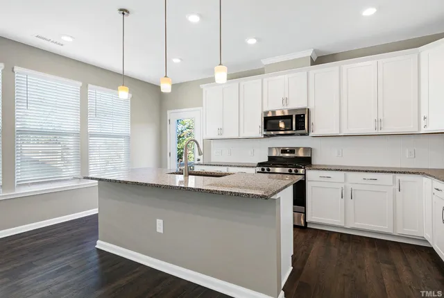 a kitchen with stainless steel appliances granite countertop a sink a stove a microwave a center island and cabinets