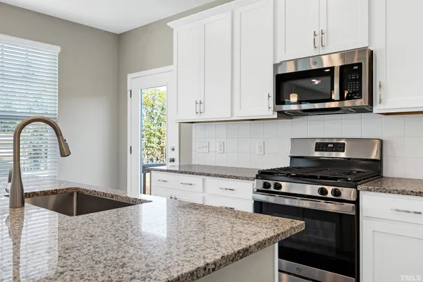 a kitchen with stainless steel appliances granite countertop a sink a stove a microwave and cabinets