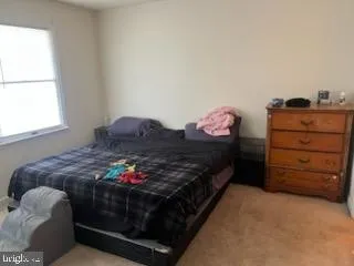 a bedroom with a bed dresser and a window