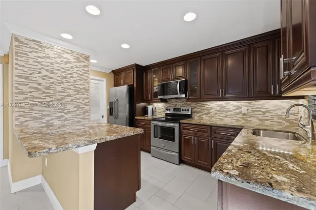 a kitchen with stainless steel appliances granite countertop a stove sink microwave and refrigerator