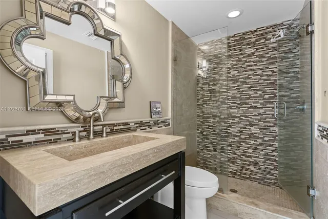 a bathroom with a granite countertop sink a toilet and mirror