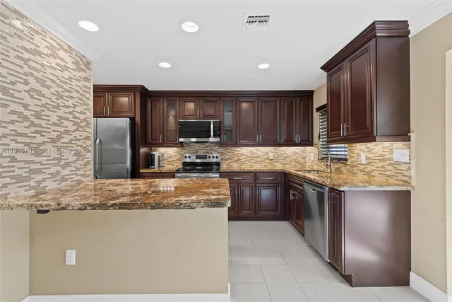 a kitchen with granite countertop stainless steel appliances a stove sink microwave and refrigerator