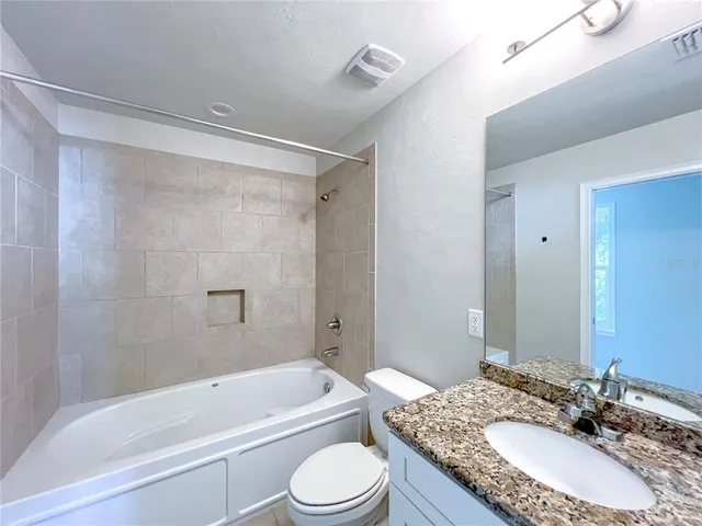 a bathroom with a granite countertop sink toilet a mirror and shower