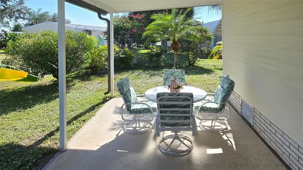 a view of a patio with table chairs and garden view