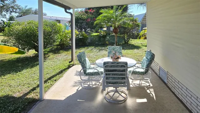 a view of a patio with table chairs and garden view