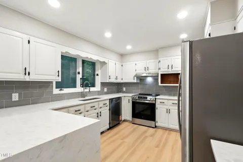 a large kitchen with stainless steel appliances granite countertop a stove and a sink