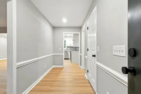 a hallway with white cabinets and wooden floor