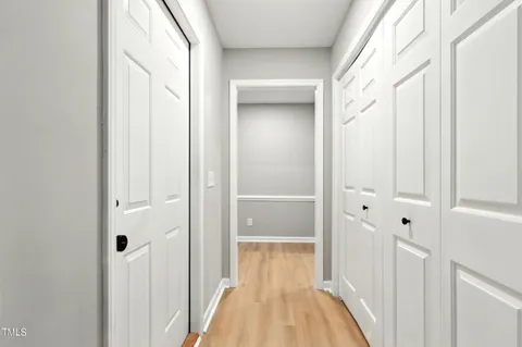 a view of a hallway with wooden floor and closet area
