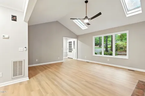 a view of an empty room with a window and wooden floor
