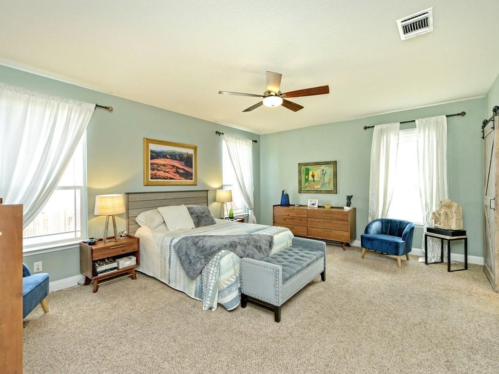 1067 Toltec Trail Georgetown, TX 78626 - Photo 12 of 30 Bedroom with light colored carpet, a ceiling fan, and a barn door