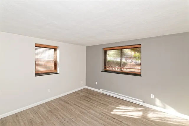 a view of an empty room with wooden floor and a window
