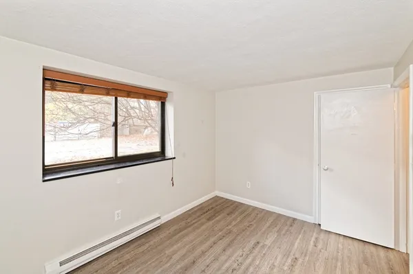 a view of hallway with window and wooden floor