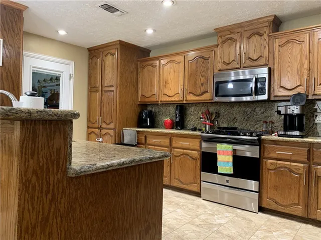 a kitchen with stainless steel appliances granite countertop a stove a sink and a microwave
