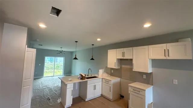 a kitchen with stainless steel appliances kitchen island granite countertop a refrigerator a stove a sink dishwasher and white cabinets with wooden floor