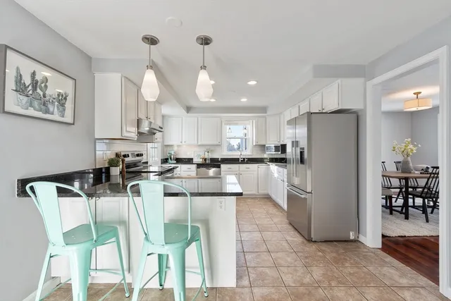 a kitchen with stainless steel appliances a refrigerator a stove a dining table and chairs