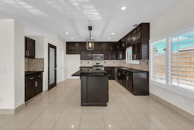 a kitchen with stainless steel appliances granite countertop a stove top oven a sink a counter space and cabinets