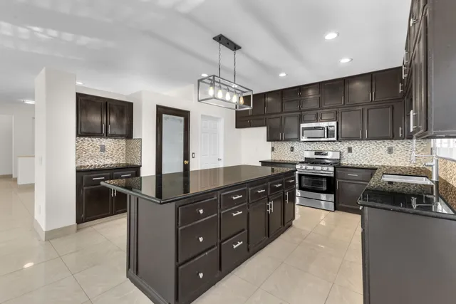 a kitchen with kitchen island granite countertop stainless steel appliances and stove top oven